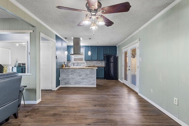 kitchen with freestanding refrigerator, extractor fan, blue cabinetry, and crown molding