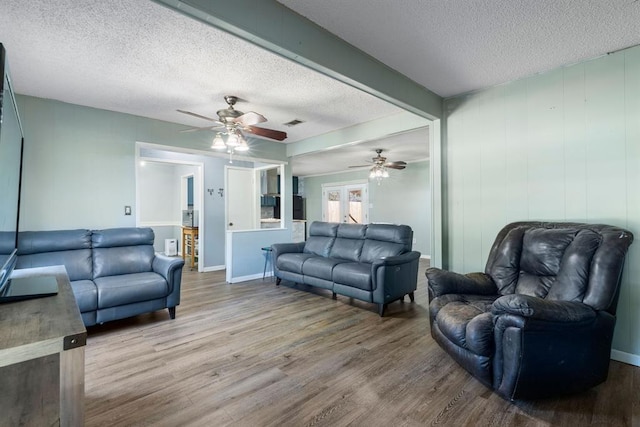 living room featuring a ceiling fan, wood finished floors, a textured ceiling, and visible vents