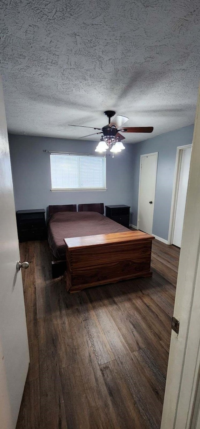 bedroom with ceiling fan, wood finished floors, and a textured ceiling