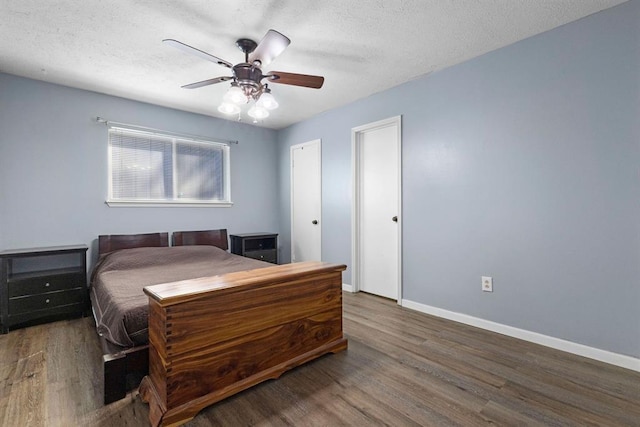 bedroom with baseboards, wood finished floors, and a textured ceiling