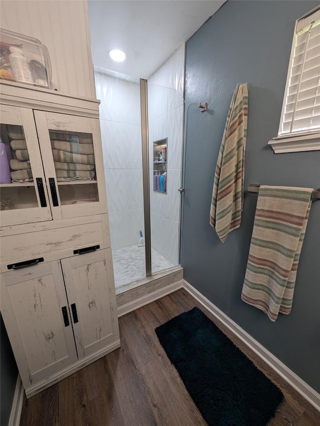 full bathroom with a tile shower, baseboards, wood finished floors, and recessed lighting
