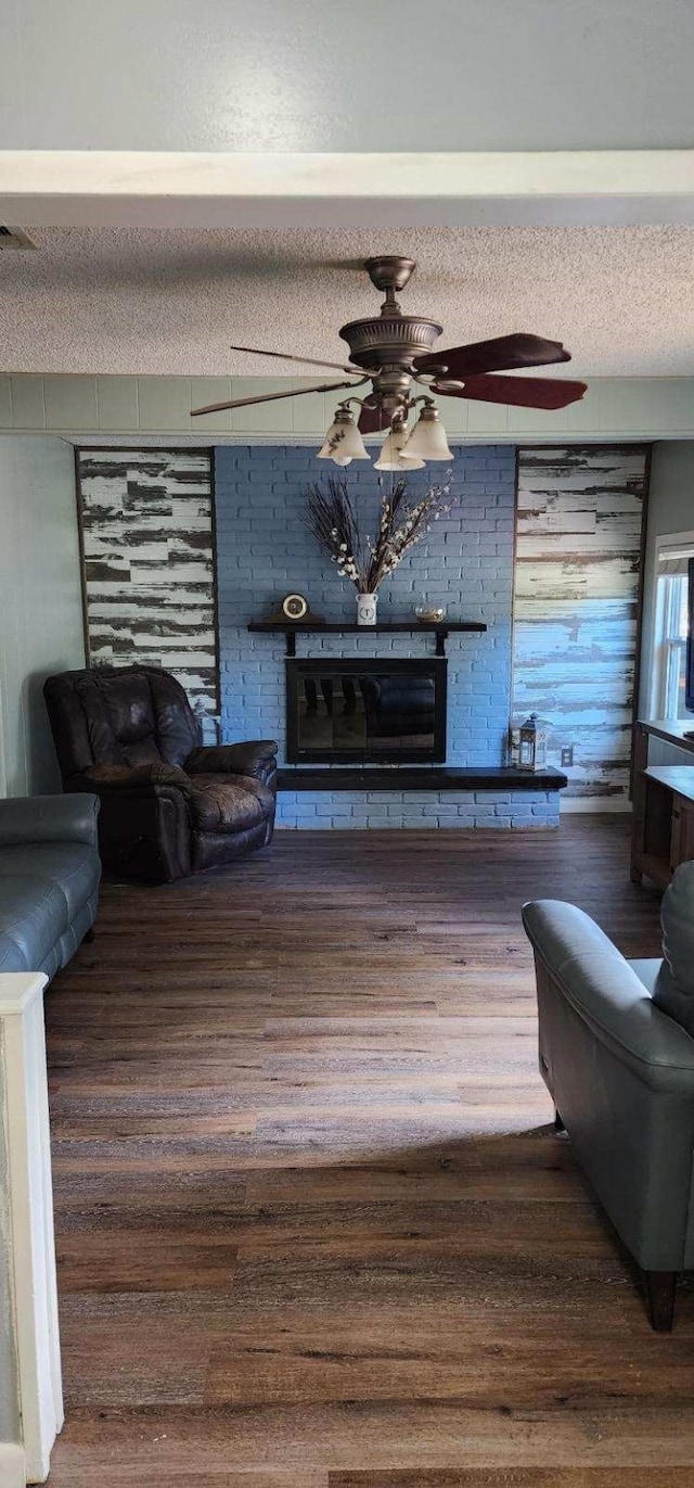 living room with a glass covered fireplace, wood finished floors, a textured ceiling, and ceiling fan