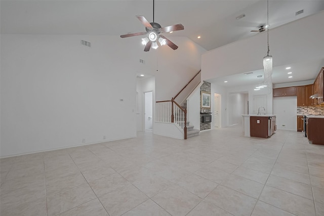 24543 Carlton Springs Ln, Katy, TX 77494 - unfurnished living room with a ceiling fan, stairs, a sink, a high ceiling, and light tile patterned flooring