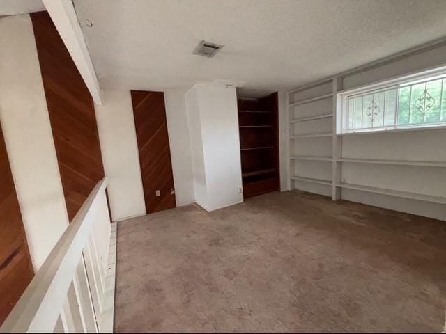 2332 Woodland Park Dr Unit 11, Houston, TX 77077 - unfurnished room featuring carpet flooring, built in shelves, a textured ceiling, and wood walls