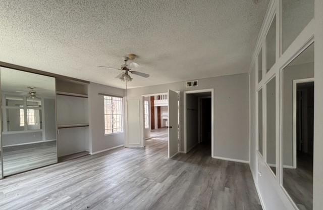 2332 Woodland Park Dr Unit 11, Houston, TX 77077 - unfurnished living room featuring ceiling fan, a textured ceiling, wood finished floors, and healthy amount of natural light