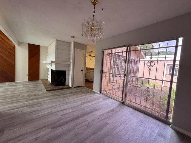 2332 Woodland Park Dr Unit 11, Houston, TX 77077 - unfurnished living room featuring a chandelier, wood finished floors, and a large fireplace