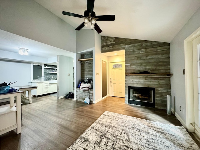 living area with baseboards, a tiled fireplace, wood finished floors, and a ceiling fan