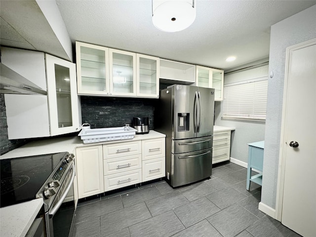 kitchen with glass insert cabinets, white cabinetry, backsplash, appliances with stainless steel finishes, and dark tile patterned floors