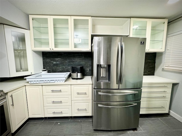 kitchen with light countertops, stainless steel fridge, dark tile patterned floors, and stove
