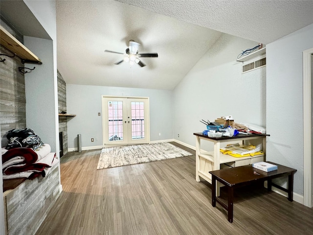 interior space featuring vaulted ceiling, wood finished floors, a textured ceiling, ceiling fan, and visible vents