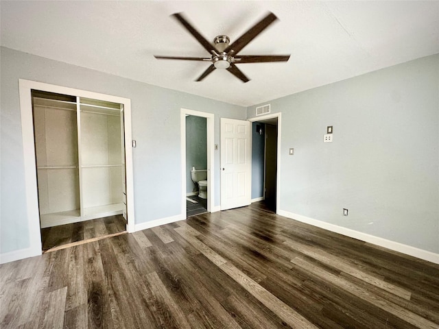 unfurnished bedroom featuring wood finished floors, a closet, baseboards, ensuite bath, and visible vents
