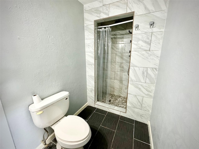 full bath with a tile shower, toilet, and baseboards