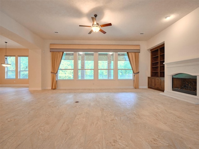 21315 Whistle Wood Dr, Richmond, TX 77406 - unfurnished living room featuring built in features, ceiling fan, and a healthy amount of sunlight