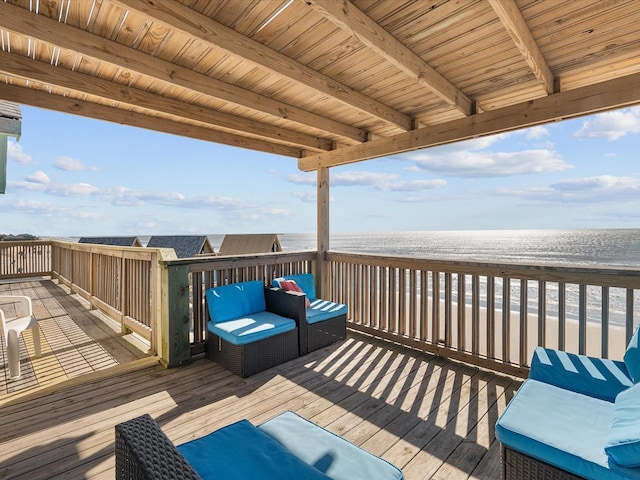 wooden terrace featuring a beach view, outdoor lounge area, and a water view