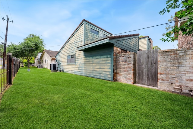 view of home's exterior featuring a yard, central AC, and fence