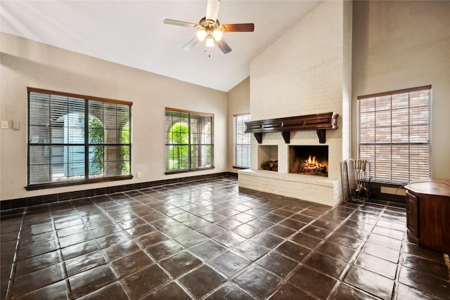 unfurnished living room with high vaulted ceiling, ceiling fan, baseboards, and a brick fireplace