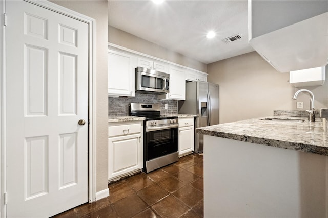 kitchen with visible vents, white cabinetry, tasteful backsplash, a sink, and appliances with stainless steel finishes
