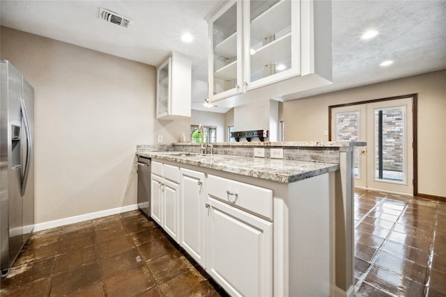 kitchen with visible vents, light stone countertops, baseboards, a peninsula, and stainless steel appliances