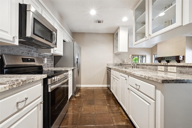 kitchen featuring appliances with stainless steel finishes, a sink, baseboards, decorative backsplash, and visible vents
