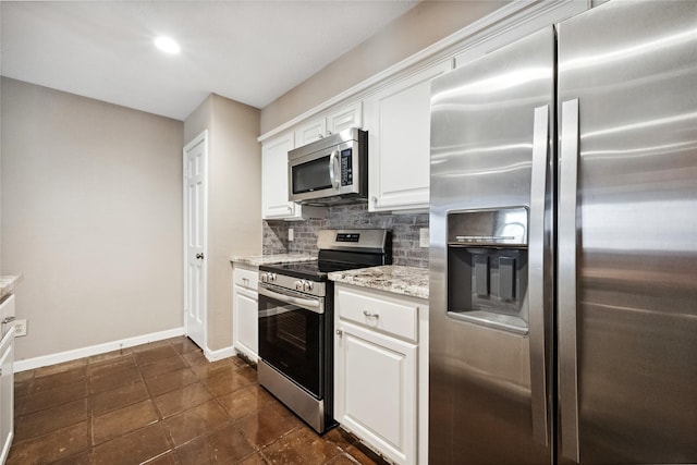 kitchen with decorative backsplash, baseboards, white cabinets, light stone counters, and stainless steel appliances