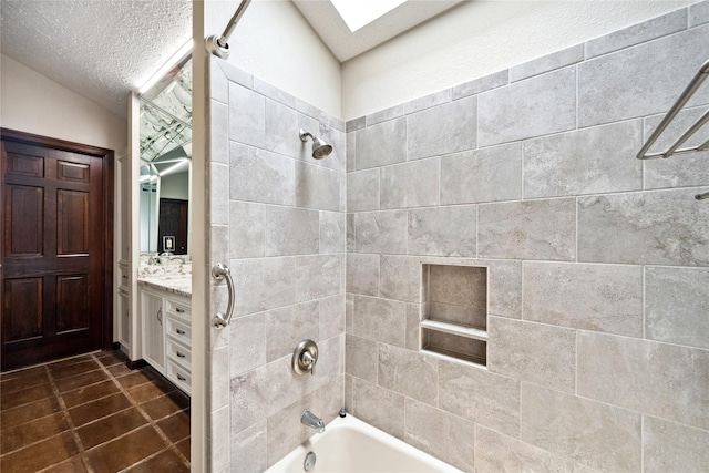 bathroom with tile patterned flooring, vanity, bathtub / shower combination, a textured ceiling, and a skylight