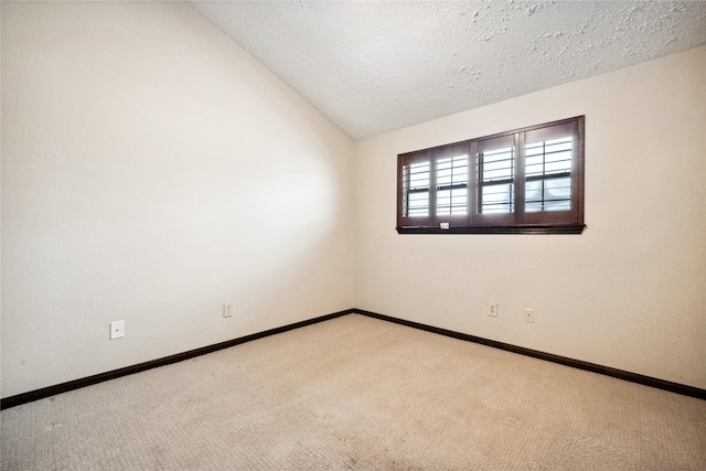 empty room with baseboards, a textured ceiling, carpet, and vaulted ceiling