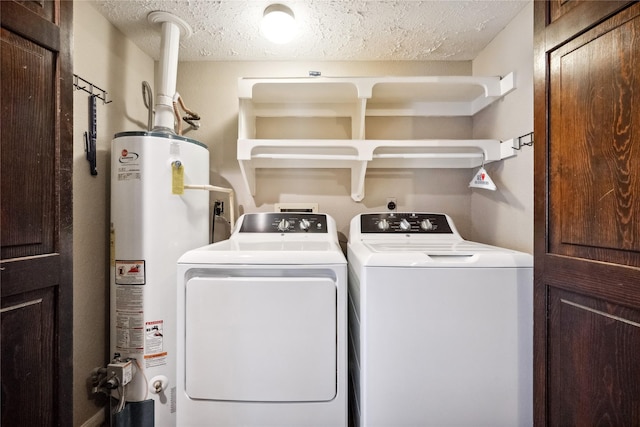 laundry room featuring washing machine and clothes dryer, a textured ceiling, laundry area, and water heater