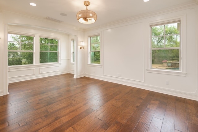 unfurnished room with dark wood finished floors, a wealth of natural light, ornamental molding, and visible vents