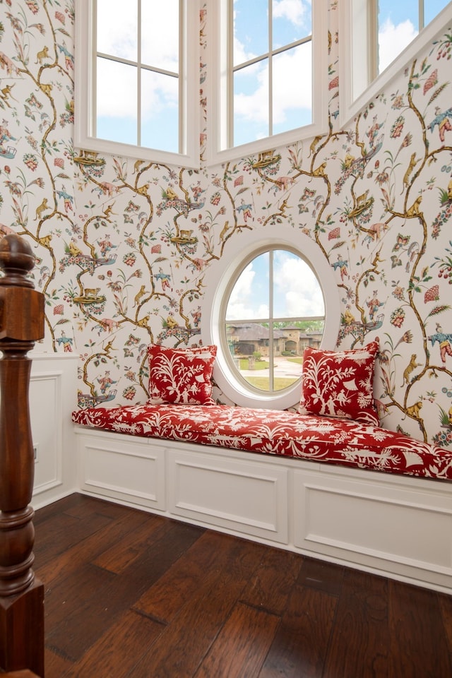 sitting room featuring wallpapered walls, a decorative wall, dark wood-style floors, and wainscoting