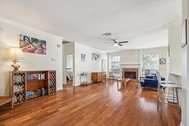 7930 Tizerton Ct, Spring, TX 77379 - living room featuring ceiling fan, wood finished floors, crown molding, a brick fireplace, and a textured ceiling