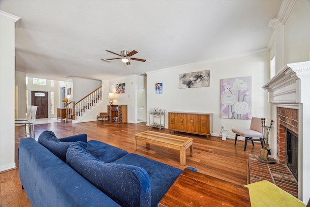 7930 Tizerton Ct, Spring, TX 77379 - living room featuring a brick fireplace, stairway, a ceiling fan, wood finished floors, and ornamental molding