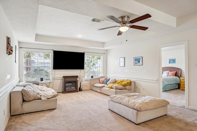 7930 Tizerton Ct, Spring, TX 77379 - living area with carpet, a tray ceiling, a ceiling fan, baseboards, and a glass covered fireplace