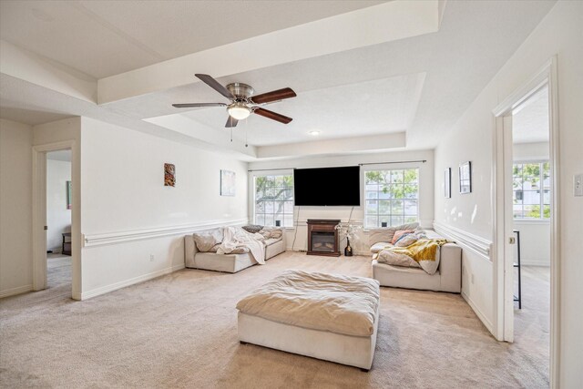 7930 Tizerton Ct, Spring, TX 77379 - living room featuring carpet flooring, a tray ceiling, a ceiling fan, a glass covered fireplace, and baseboards