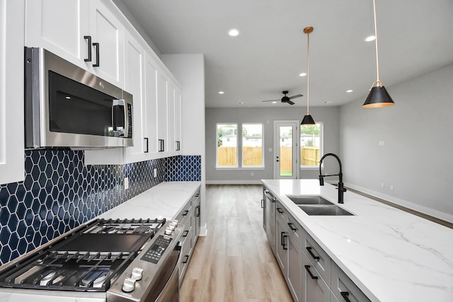 6817 Peerless St, Houston, TX 77021 - kitchen with light wood finished floors, a sink, tasteful backsplash, ceiling fan, and appliances with stainless steel finishes