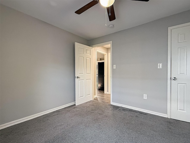unfurnished room with dark carpet, baseboards, and ceiling fan