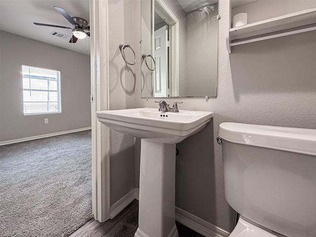 half bath with a ceiling fan, a sink, baseboards, toilet, and visible vents