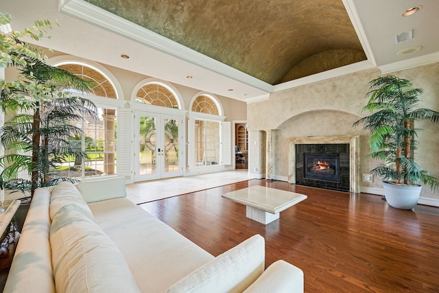living room with hardwood / wood-style floors, french doors, a high end fireplace, and ornamental molding