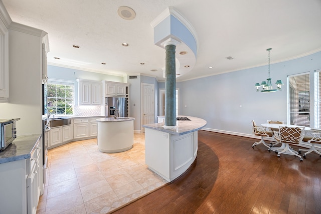 kitchen featuring light stone counters, appliances with stainless steel finishes, a center island, and ornamental molding