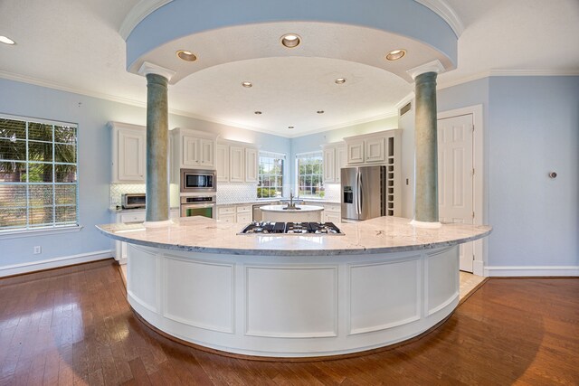 13602 Copeland Oaks Blvd, Cypress, TX 77429 - kitchen with stainless steel appliances, ornate columns, a large island, dark wood-type flooring, and backsplash