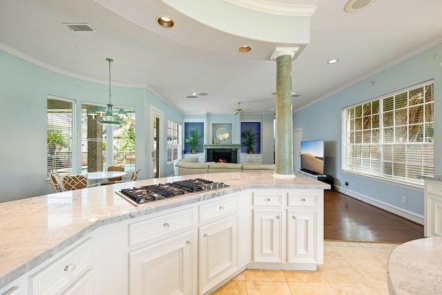 kitchen featuring light stone counters, visible vents, crown molding, and stainless steel gas cooktop