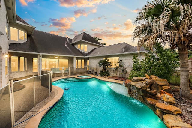 pool at dusk featuring a patio area and a pool with connected hot tub
