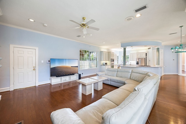living area featuring ornate columns, a ceiling fan, visible vents, and ornamental molding