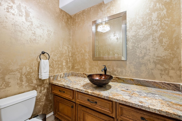 bathroom with wallpapered walls, toilet, and vanity