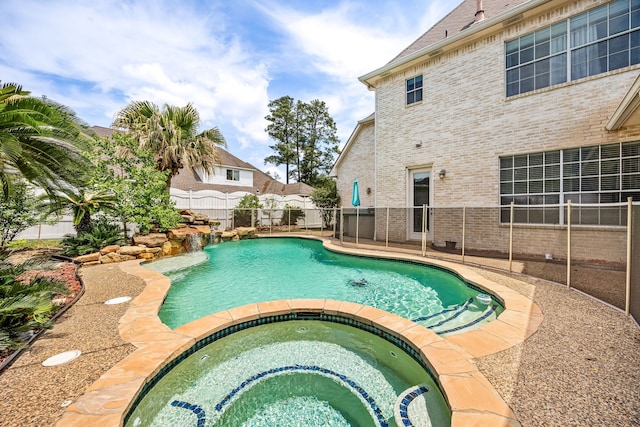 view of pool featuring fence and a pool with connected hot tub