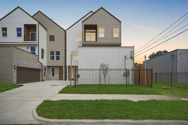 view of front of property with concrete driveway, fence, stone siding, and a front yard
