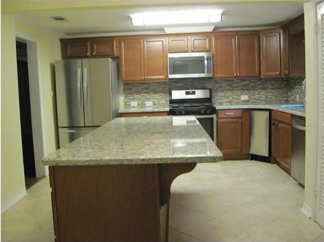 kitchen with a center island, a sink, appliances with stainless steel finishes, and tasteful backsplash