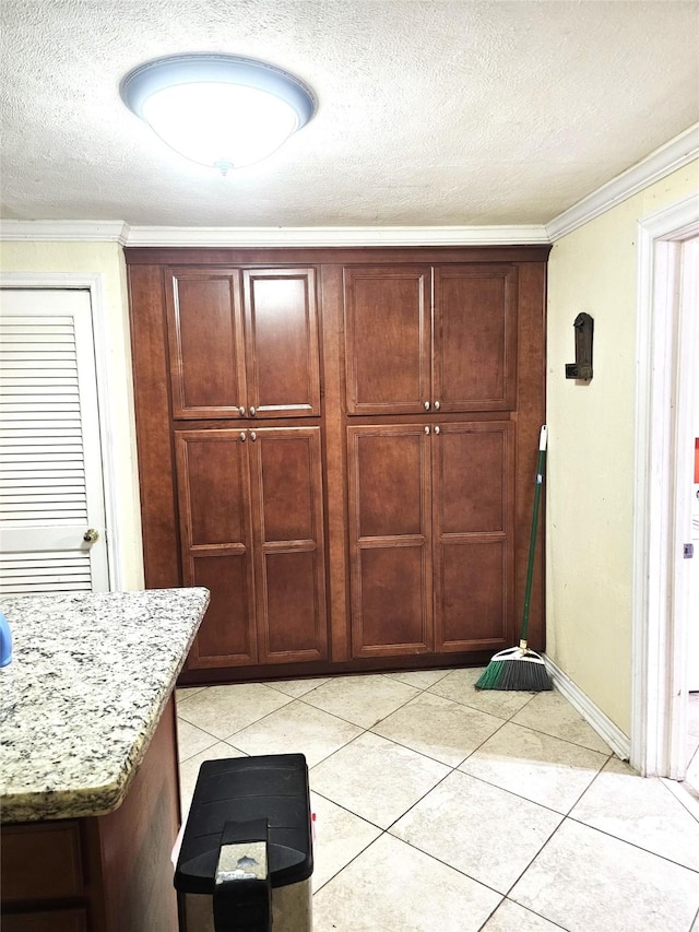 doorway with baseboards, ornamental molding, a textured ceiling, and light tile patterned flooring