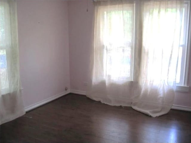 empty room featuring baseboards, wood finished floors, and a healthy amount of sunlight