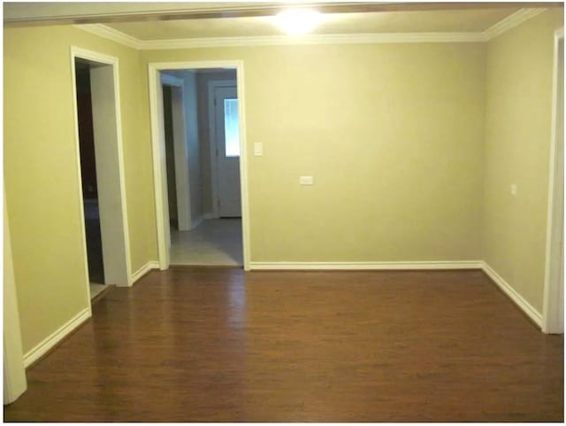 spare room with baseboards, dark wood-style floors, and ornamental molding