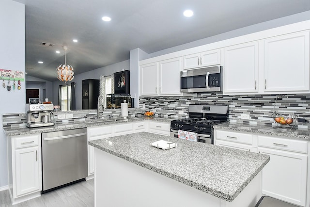 kitchen with stainless steel appliances, a center island, decorative backsplash, and white cabinetry